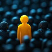 Conceptual image of a unique yellow person standing out in a sea of dark figures, representing brand differentiation and standing out from the